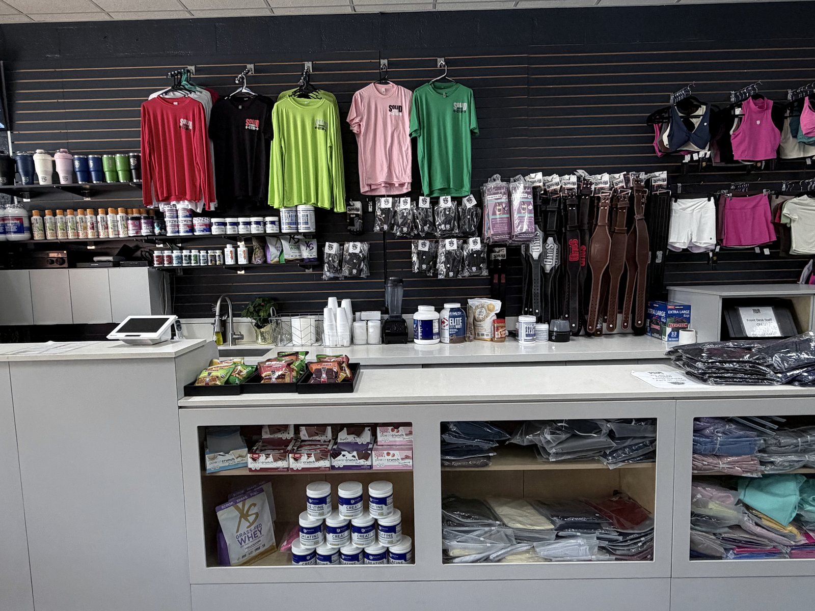 The pro shop wall at the front desk with gym apparel and supplements